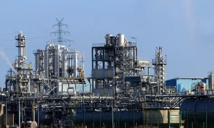 Silhueta anónima diante de tanques de refinaria costeira em dia claro