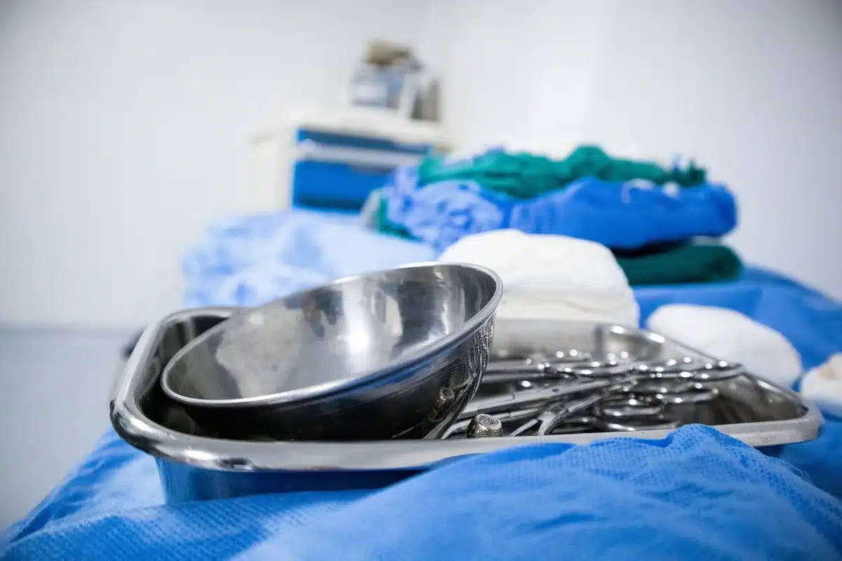 Wide shot of an empty operating theatre with a surgical light, a sterile drape on the table, and an unbranded headset on a tray suggesting device testing