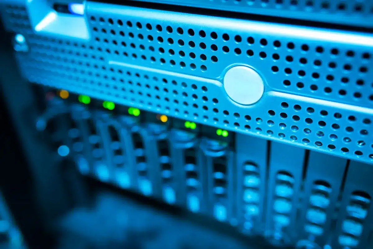 Empty server room racks under blue LED light, one technician silhouette blurred in background