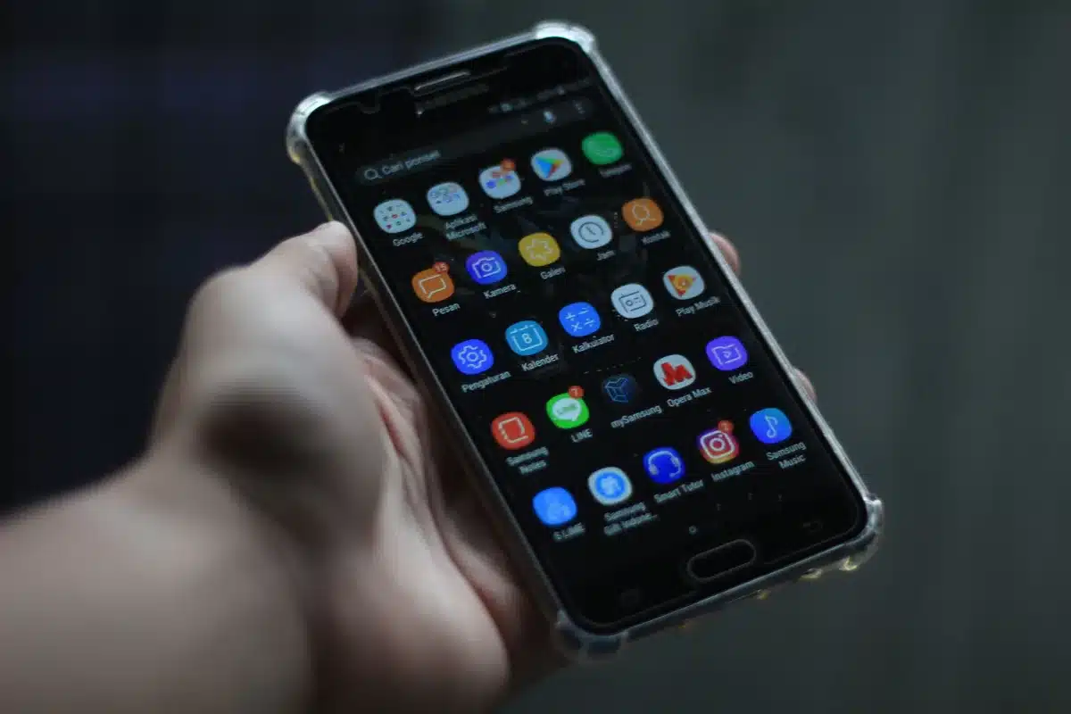 Close-up of an anonymous hand holding an unbranded smartphone showing a vivid AMOLED screen, blurred store environment in background