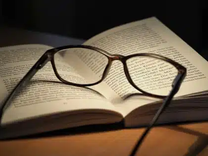 Mãos com luvas a folhear um livro antigo numa mesa de arquivo