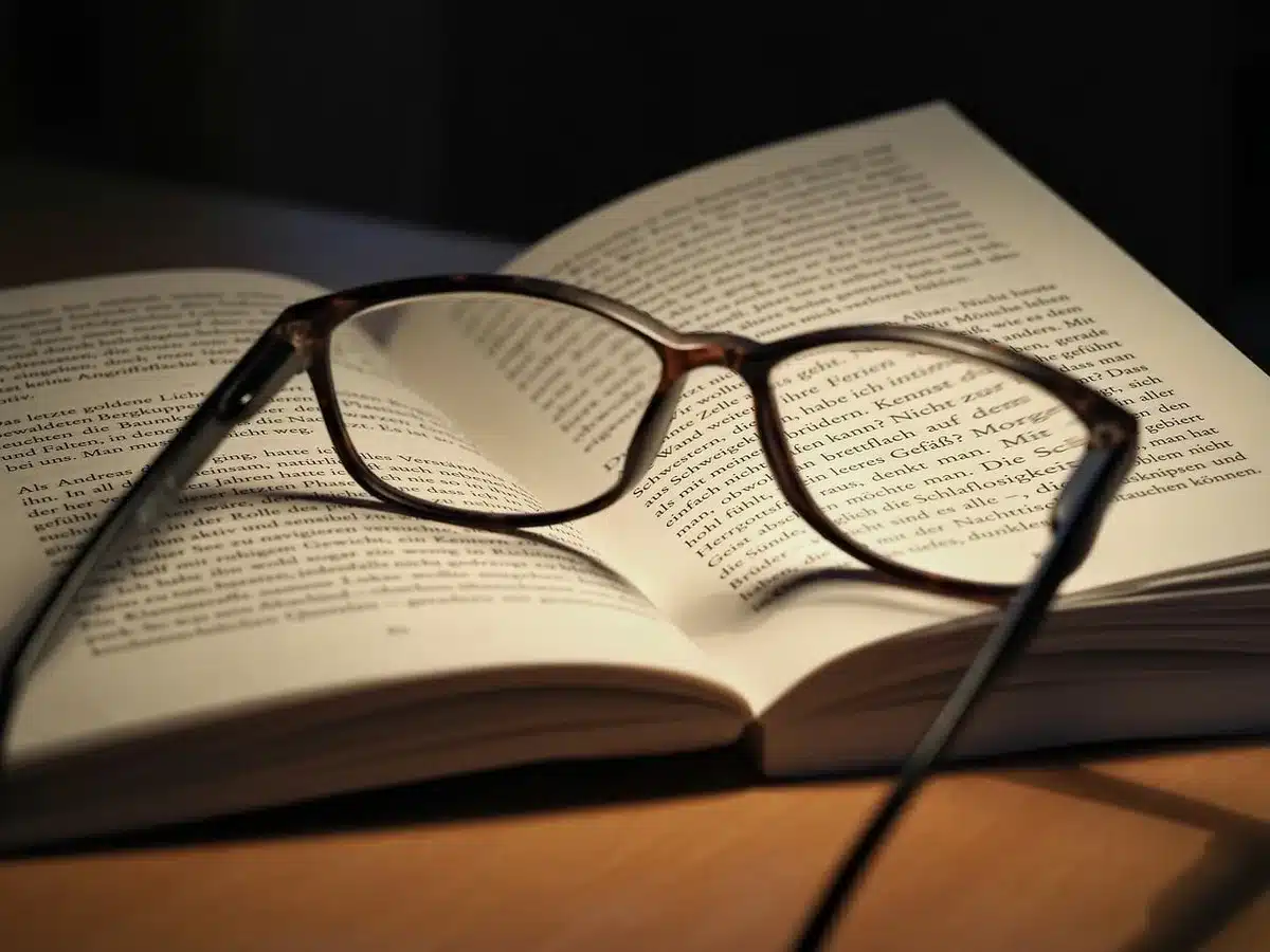 Mãos com luvas a folhear um livro antigo numa mesa de arquivo