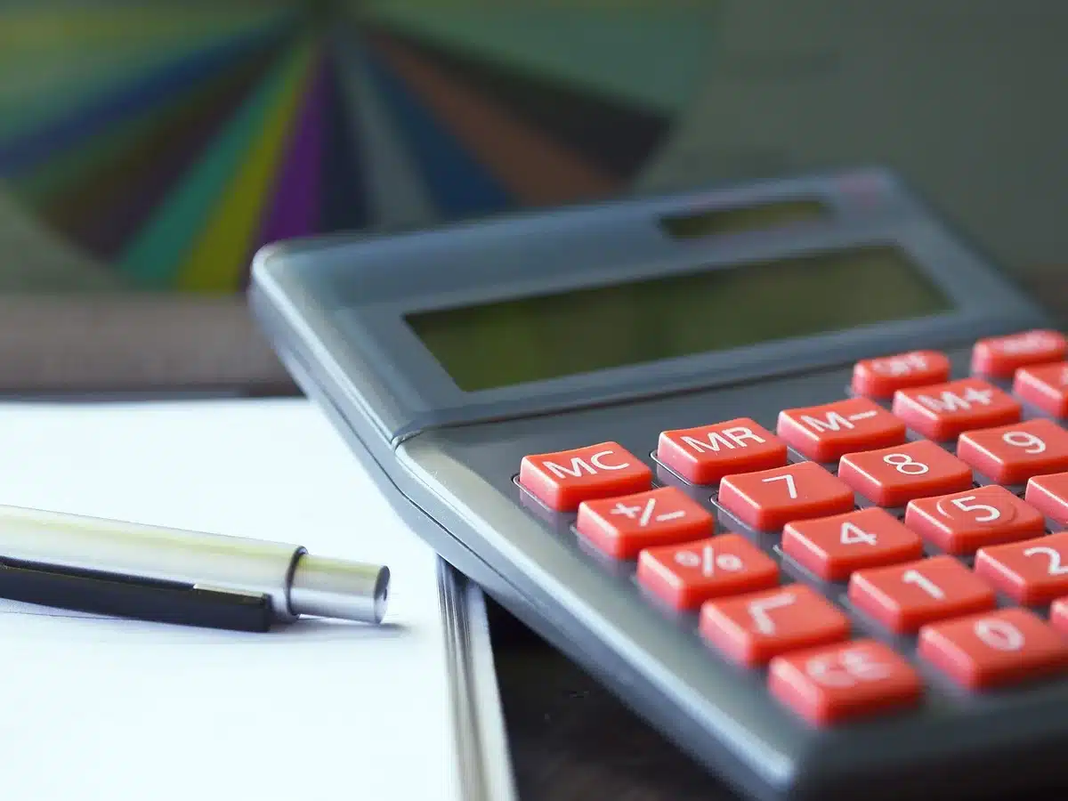 Pessoa anónima a calcular poupanças com moedas e calculadora