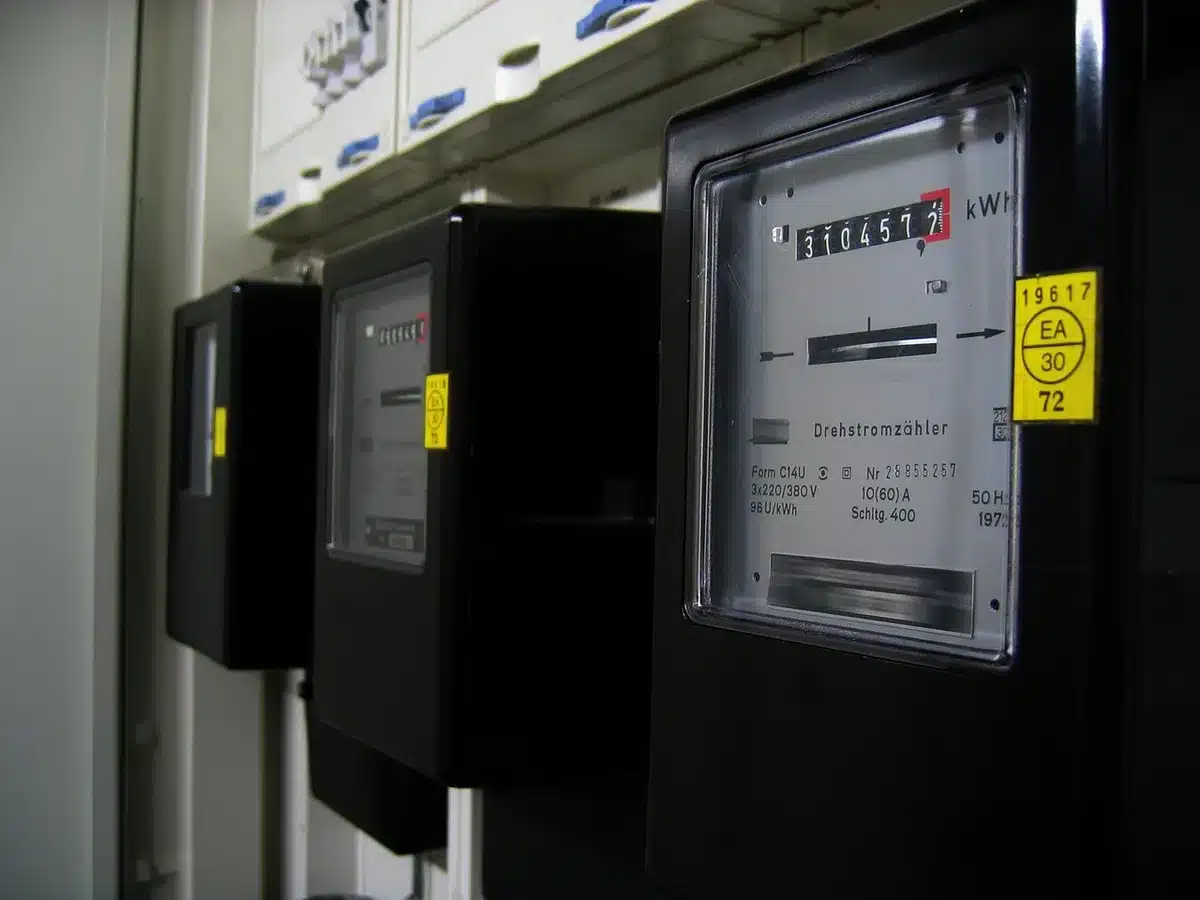 Anonymous silhouette looking at a glowing home meter display, interior dimly lit, no identifiable person