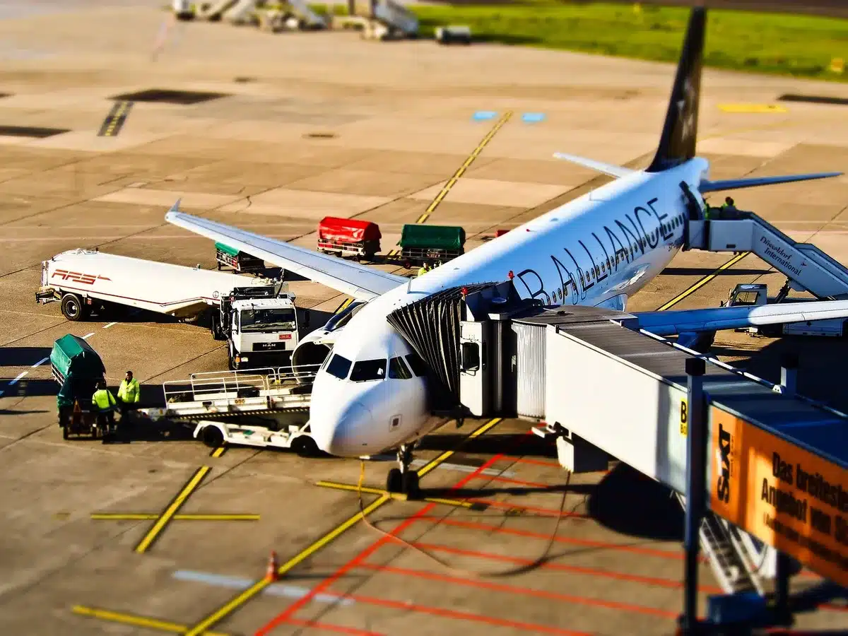 empty airport gate at dusk, few anonymous travelers with carry-ons, departure display blurred