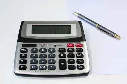 Mãos anónimas a contar recibos com calculadora e pasta de finanças desfocada