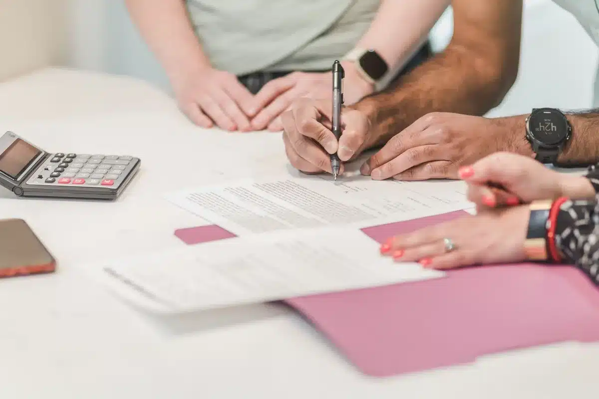 Anonymous hands holding a stack of rental contracts and utility bills on a kitchen table