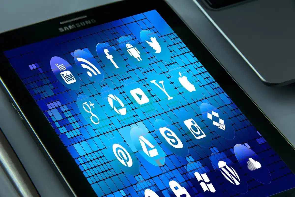 Livros sobre mesa e smartphone com mensagens, simbolizando impacto digital na escrita