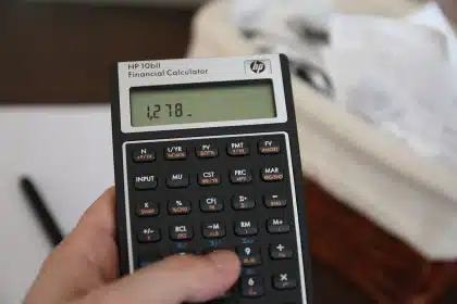Mãos a organizar recibos, extratos e uma calculadora sobre uma mesa doméstica